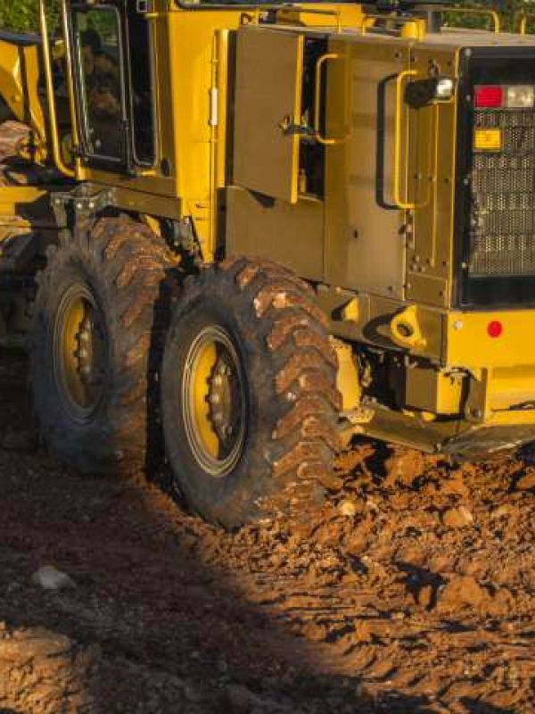 Grader is working on road construction. Grader industrial machine on construction of new roads. Heavy duty machinery working on highway. Construction equipment. Compaction of the road.